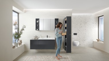Woman opens tall cabinet with lots of storage space in bathroom with Geberit Acanto bathroom furniture